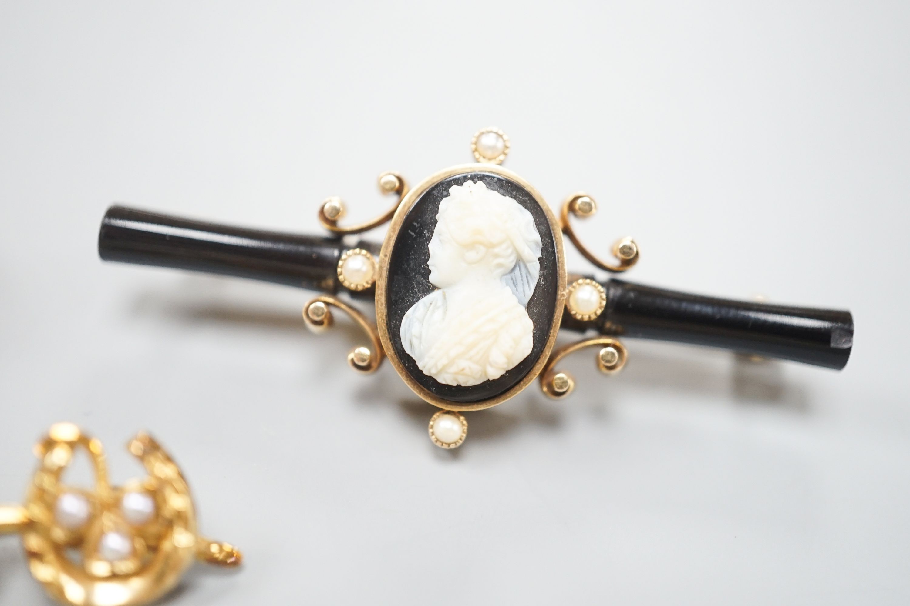A 19th century yellow metal and white carnelian intaglio set ring, with crest and motto (a.f.), a yellow metal, sardonyx cameo, black onyx and seed pearl set bar brooch, 52mm, a Victorian gold triple horseshoe and seed p